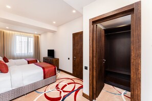 Habitación de hotel con cama, televisión, armario y alfombra de diseño geométrico.