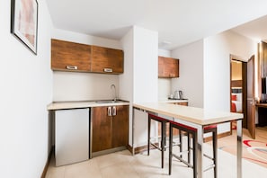 Une cuisine de taille réduite, avec des meubles de rangement en bois, un évier et un coin bar.
