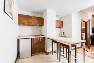 Een kleine keuken met houten kastjes, een spoelbak en een bar.