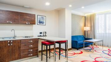 A modern kitchen with a bar area, a sofa, and a lamp.