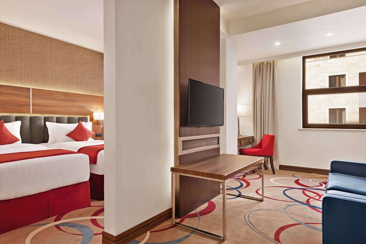 Une chambre d’hôtel avec un grand lit, un téléviseur fixé au mur, un bureau et une chaise.