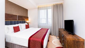 Een hotelkamer met een groot bed, een televisie en een houten dressoir.