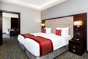 Una habitación de hotel con una cama grande, dos mesitas de noche, un escritorio y una silla.