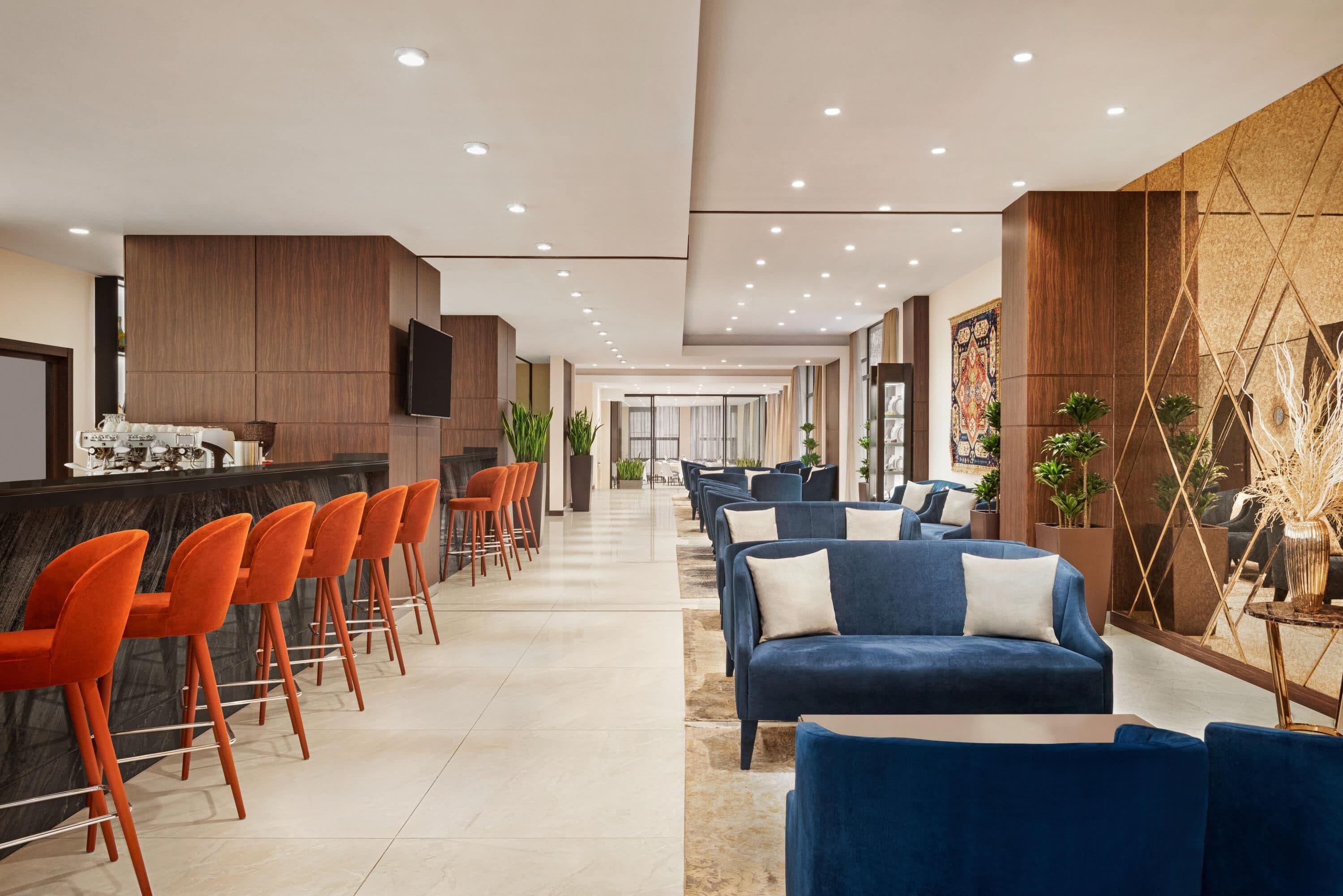 Een moderne lobby met een bar, zitplaatsen en een groot scherm.