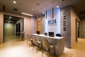 Een receptiebalie met een bord waarop staat 'fit24 FITNESS CLUBS' en 'BE FIT 24/7'.