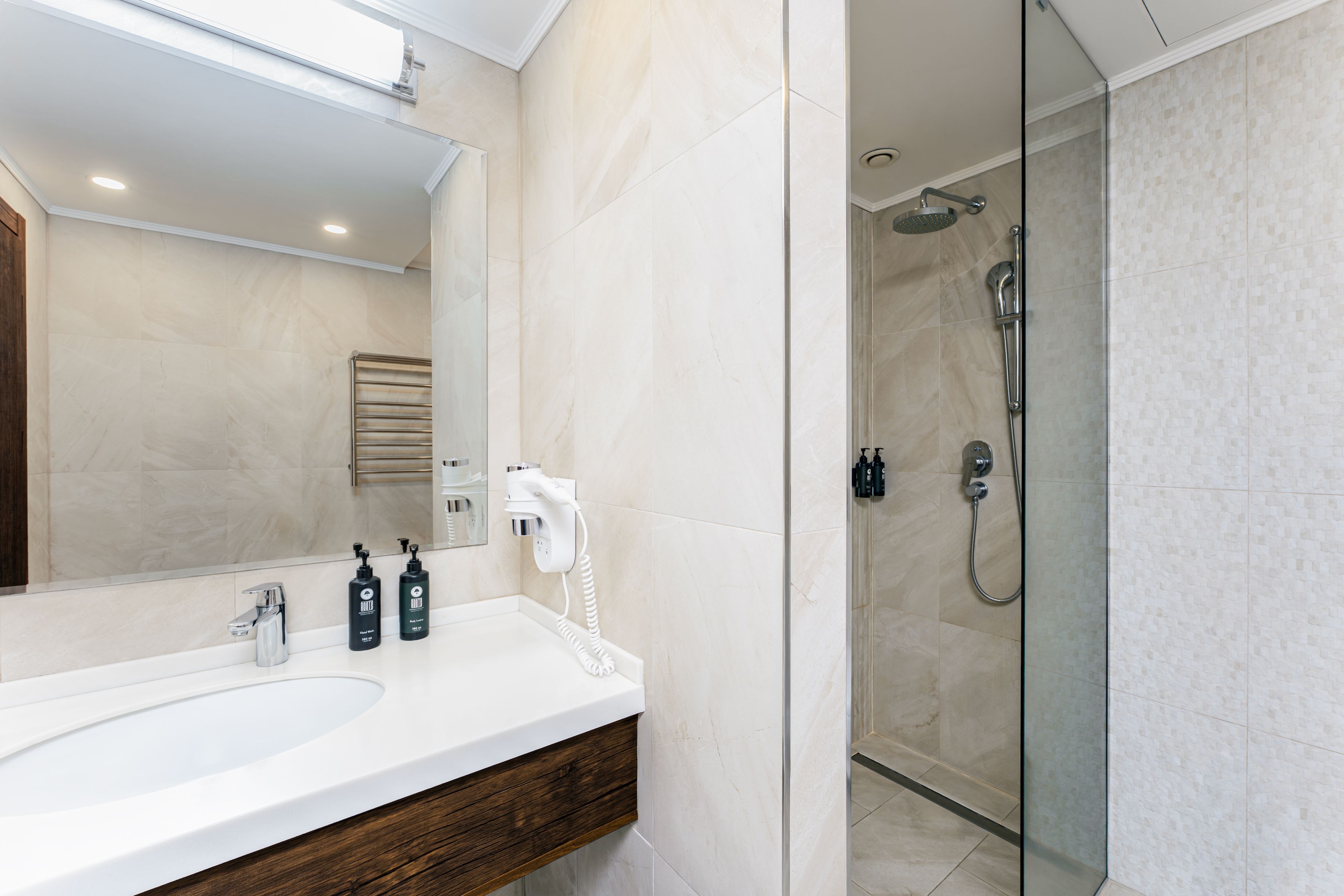 Un baño moderno con un espejo grande, un lavabo y una zona de ducha.