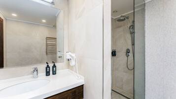 Un baño moderno con un espejo grande, un lavabo y una zona de ducha.