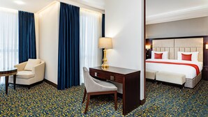 Een hotelkamer met een bed, bureau, stoel en een klein tafeltje.