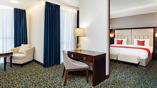Une chambre d’hôtel avec un lit, un bureau, une chaise et une petite table.