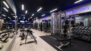 Een moderne sportschool met diverse fitnessapparaten, een motiverende poster en een gewichthefzone.