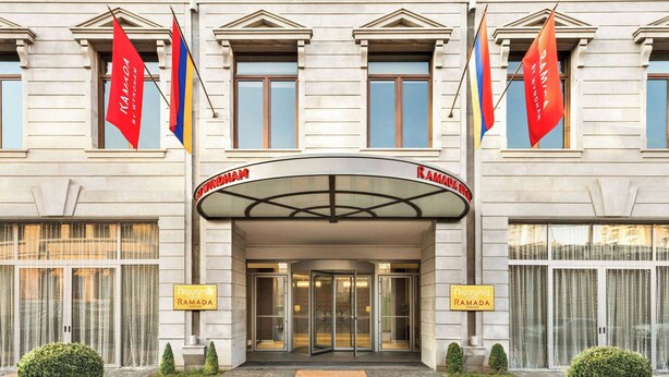 Een hotelentree met een klassiek gevelontwerp, dubbele deuren en twee vlaggen.