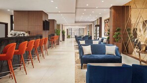 Een moderne hotel lobby met een bar, zitplaatsen en een groot televisiescherm.