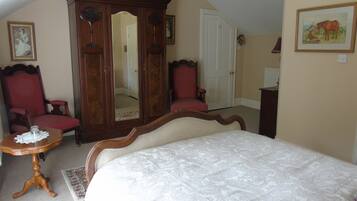 Una camera da letto con un letto grande, un'armadietto in legno, una sedia rossa e un tavolino.