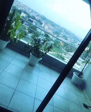 A balcony with potted plants and a city view. - Residence djoumah (Abidjan)