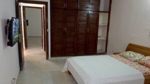 A bedroom with a bed, a wardrobe, and a television on the wall. - Residence djoumah (Abidjan)
