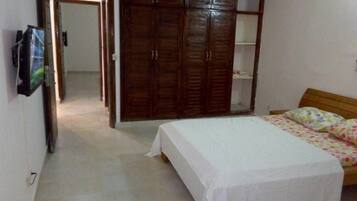 Quarto com uma cama, um guarda-roupa e uma televisão na parede.