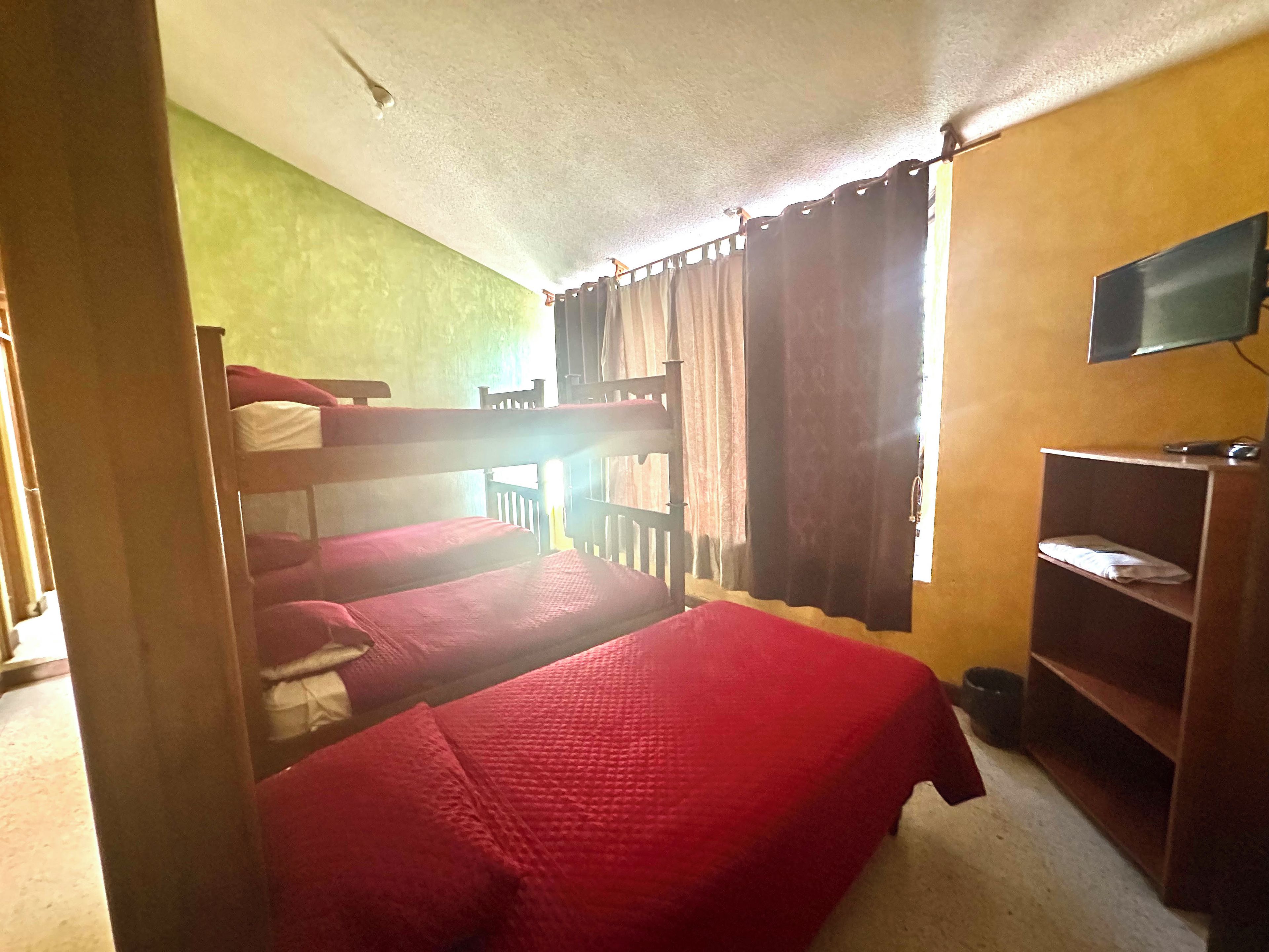 Una habitación con literas, un televisor y una estantería con objetos.
