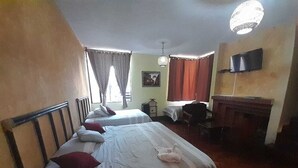 Une chambre d’hôtel avec deux lits, un bureau, une chaise, une télévision et une cheminée.