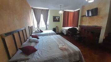 Une chambre d’hôtel avec deux lits, un bureau, une chaise, une télévision et une cheminée.