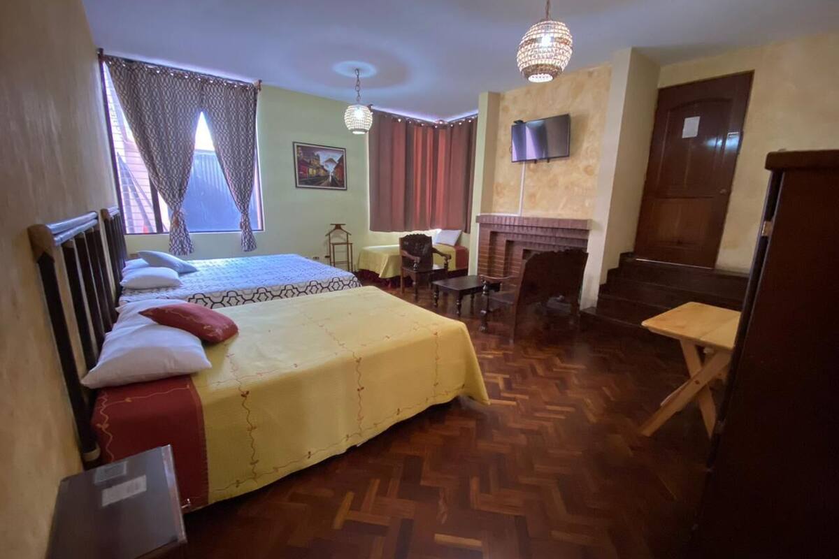 Ein Hotelzimmer mit Bett, Schreibtisch, Stuhl, Kamin und Fernseher.