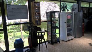 A room with a wooden floor, a glass cabinet, a refrigerator, and a fan. - Johmer Expedition Tours & Lodge (Iquitos)