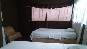 A room with two beds, a chair, and a window with curtains. - Johmer Expedition Tours & Lodge (Iquitos)
