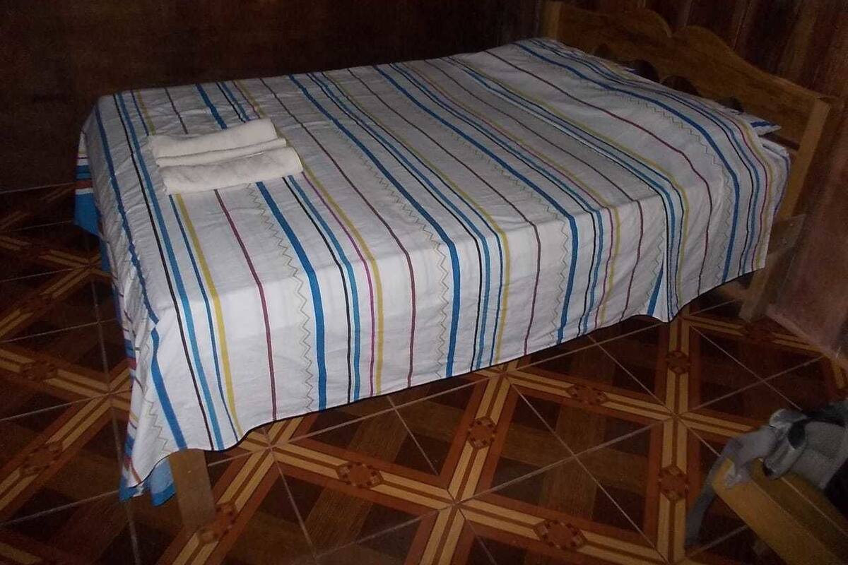 A bed with a striped bedspread and a folded towel on it.