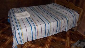 Una cama con una colcha a rayas y una toalla doblada.