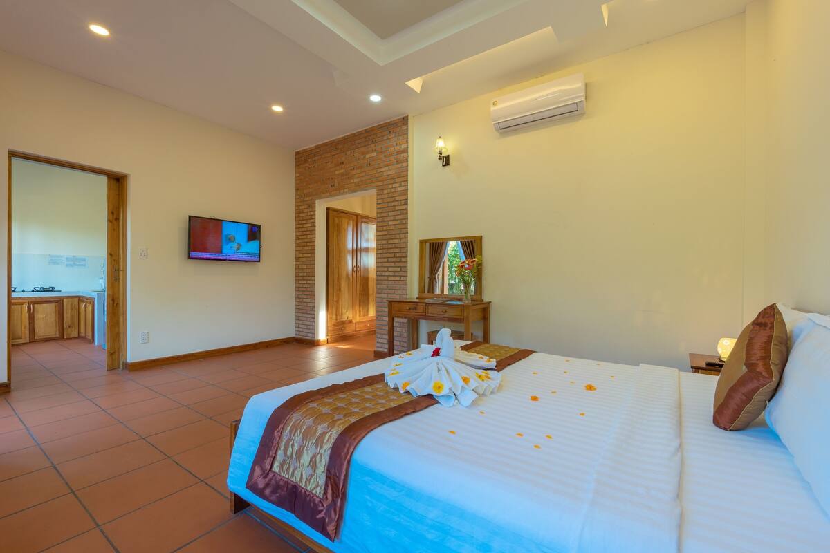 A hotel room with a bed, a television, a desk, and a bathroom visible through an open door.