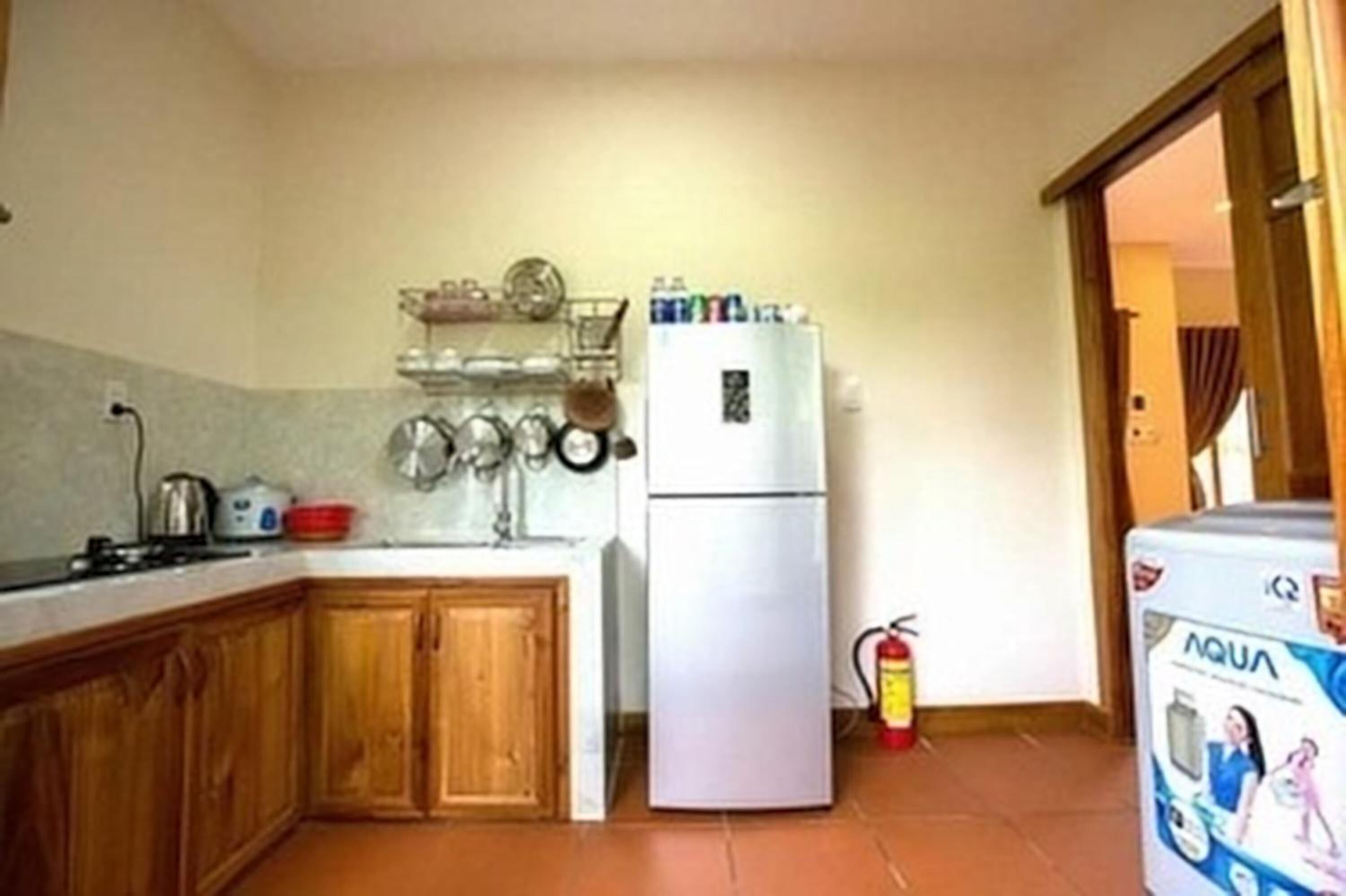 Una cocina compacta con armarios de madera, un refrigerador blanco y un dispensador de agua.