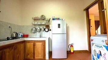 Una cocina compacta con armarios de madera, un refrigerador blanco y un dispensador de agua.
