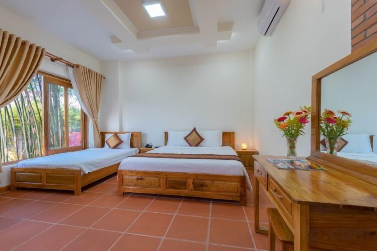 Una habitación con dos camas de madera, un escritorio de madera, un espejo y una ventana con cortinas.