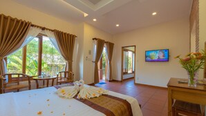 A hotel room with a bed, a TV, a dining area, and a view of the outdoors. - Phu Quoc Bungalow Yen Thanh (Phu Quoc)