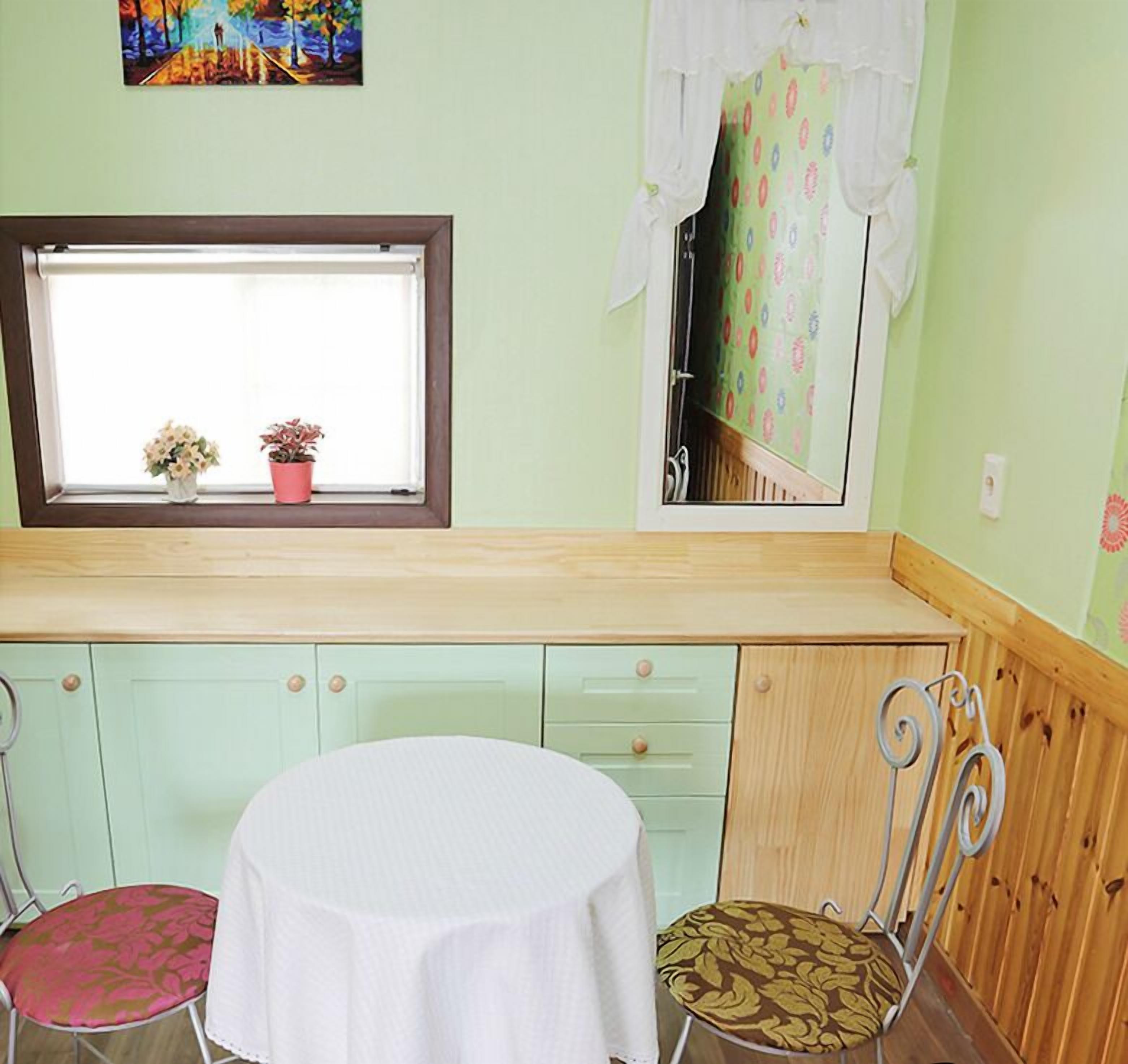 A small room with a window, a table, two chairs, and a cabinet with drawers.