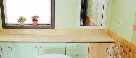 A small room with a window, a table, two chairs, and a cabinet with drawers.