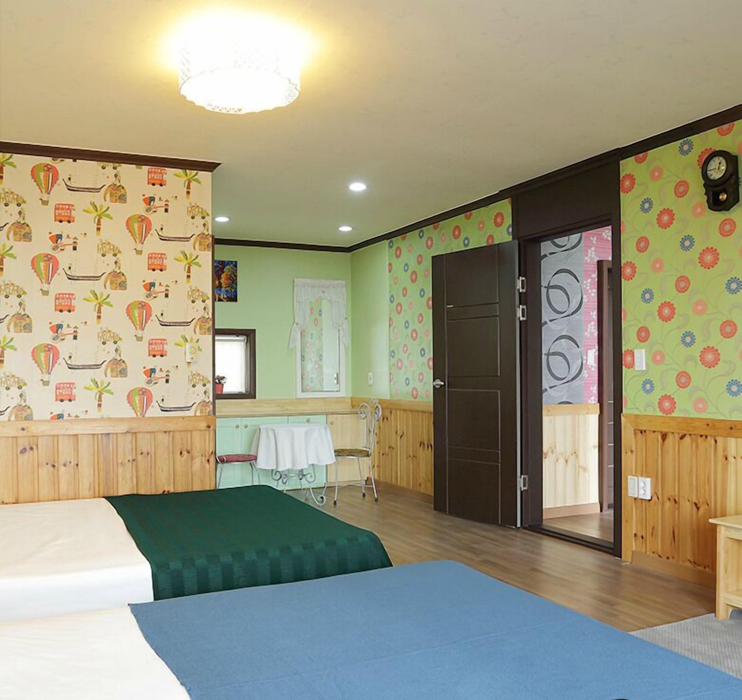 Ein Zimmer mit zwei Betten, einem Holzschrank, einem kleinen Tisch und einer Tür zu einem Badezimmer.