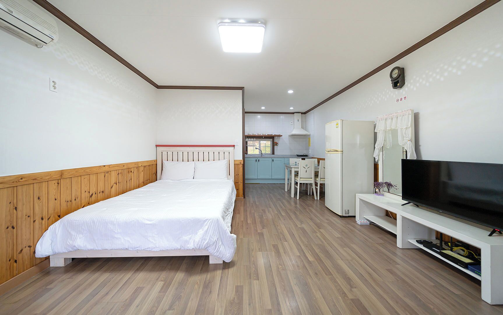 A hotel room with a bed, a TV, a kitchenette, and a dining area.