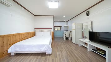 Una habitación de hotel con cama, televisión, kitchenette y zona de comedor.