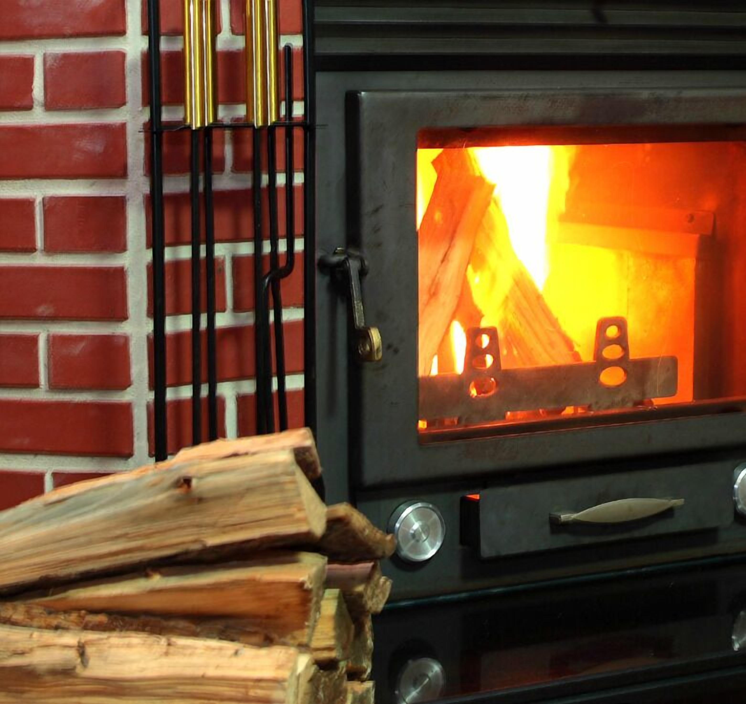 Puuilla lämmitettävä kamiina, jossa näkyy tuli, tiiliseinä ja metallinen ritilä.