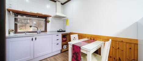 Eine kleine Küche mit weißen Schränken, einer Holz Arbeitsplatte, einem Fenster über der Spüle und einem Tisch mit Stühlen.