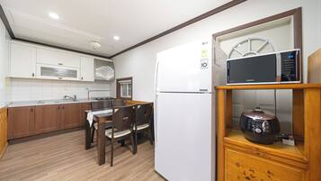 Cocina compacta con armarios blancos, un refrigerador blanco, un microondas y un mueble de madera con un adorno.