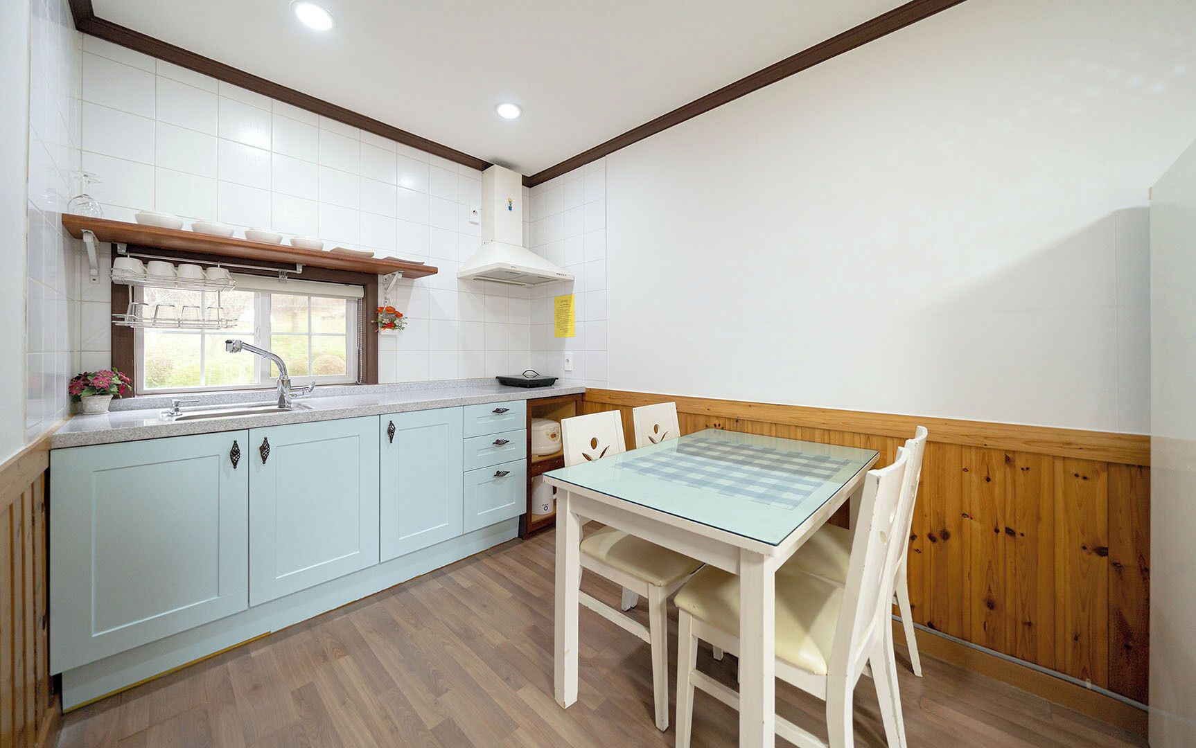 A kitchen with light blue cabinets, a wooden countertop, a sink, and a table with chairs.
