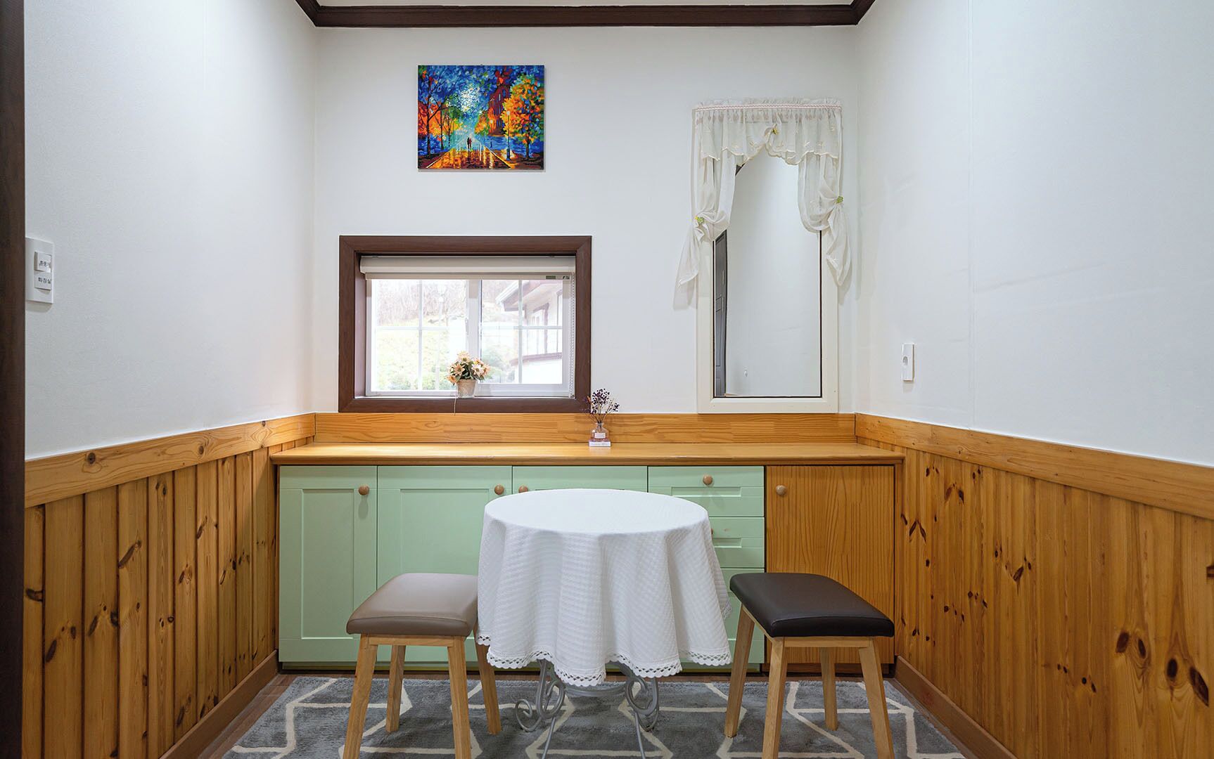 A small kitchen with a window, a table, and two stools.