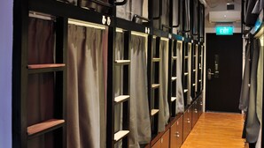 A row of bunk beds with curtains, a wooden floor, and an exit sign.