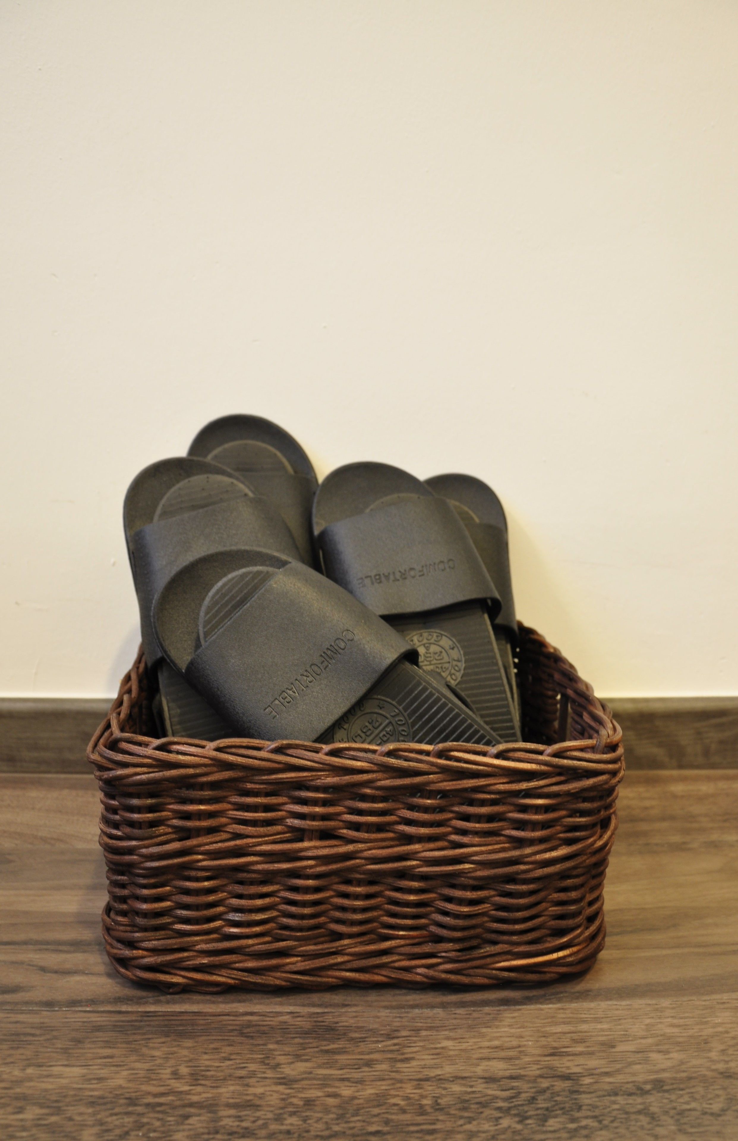 Een rieten mand met zwarte slippers met zichtbare branding.