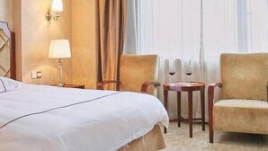 A hotel room with a large bed, two armchairs, a small table with a wine glass, and a window with sheer curtains. - Hangzhou Wangsu Hotel Letong (Hangzhou)