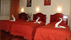 A hotel room with two beds, each with a swan-shaped towel and a vase of flowers. - inkayra hotel (Cusco)