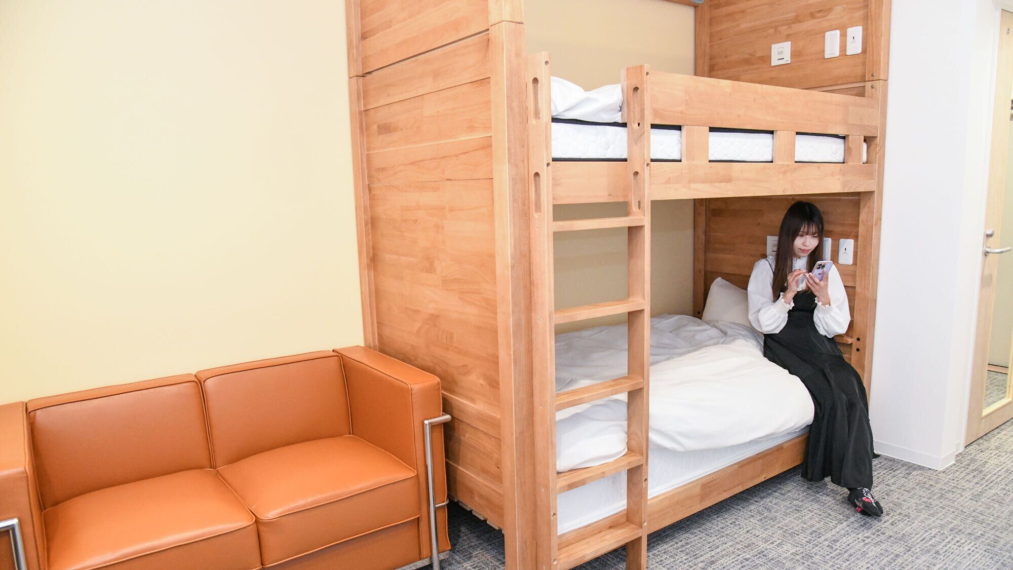 Un lit superposé avec une structure en bois, un lit simple et un canapé.