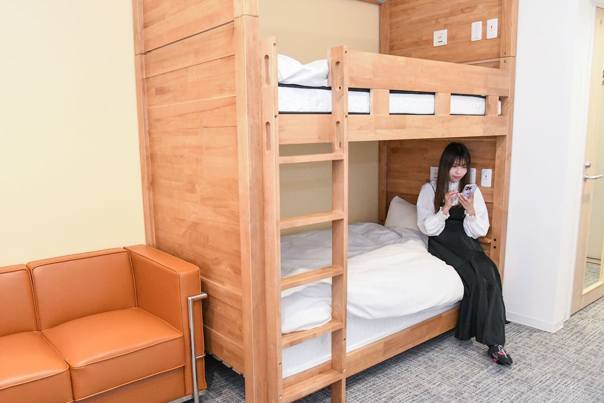 Un lit superposé avec une structure en bois, un lit simple et un canapé.