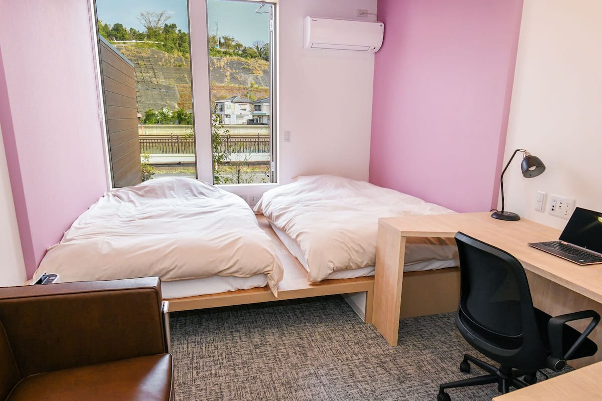 Une petite pièce comprenant un lit, un bureau, une chaise et un ordinateur portable.